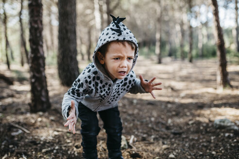 Porträt eines kleinen Jungen mit Kapuzenjacke, der im Wald ein Monster spielt - JRFF01044