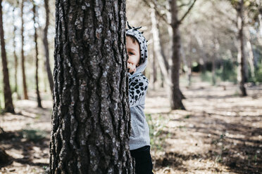 Kleiner Junge versteckt sich hinter einem Baumstamm im Wald - JRFF01046