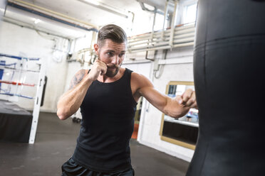 Boxer exercising at punch bag - MADF01229