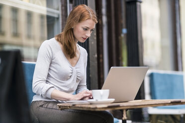 Redheaded woman using laptop at sidewalk cafe - TAMF00815