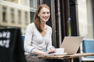 Rothaarige Frau mit Laptop in einem Straßencafé - TAMF00816