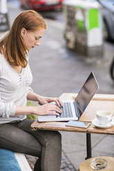 Redheaded woman using laptop at sidewalk cafe - TAMF00818