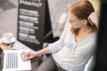 Rothaarige Frau mit Laptop in einem Straßencafé - TAMF00819