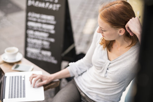 Redheaded woman using laptop at sidewalk cafe - TAMF00819