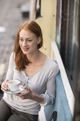 Rothaarige Frau trinkt Kaffee in einem Straßencafé, lizenzfreies Stockfoto