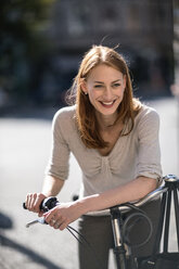 Portrait of redheaded woman with bicycle - TAMF00825