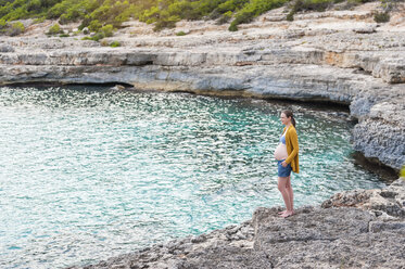 Schwangere Frau steht auf einem Felsen am Meer - DIGF01443