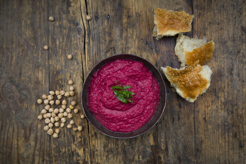 Schale mit Rote-Bete-Hummus, Kichererbsen und Fladenbrot auf dunklem Holz - LVF05578