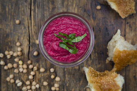 Glass of beetroot hummus, chick-peas and flat bread on dark wood stock photo