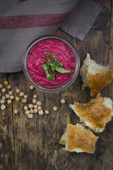 Glas Rote-Bete-Hummus, Kichererbsen und Fladenbrot auf dunklem Holz - LVF05584