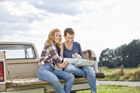 Couple sitting on pick up truck reading map - FMKF03186