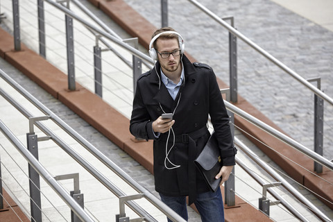 Junger Mann mit Kopfhörern und Mobiltelefon im Freien, lizenzfreies Stockfoto