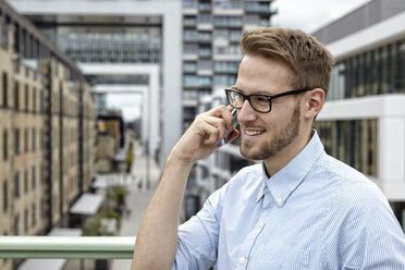 Smiling young man on cell phone outdoors - FMKF03235