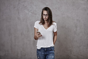 Junge Frau schaut auf ein Mobiltelefon - FMKF03243