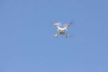 Fliegende Drohne mit Kamera vor blauem Himmel - MMAF00011