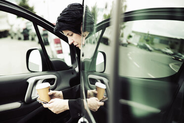 Businesswoman sitting in car, using smart phone - JATF00924