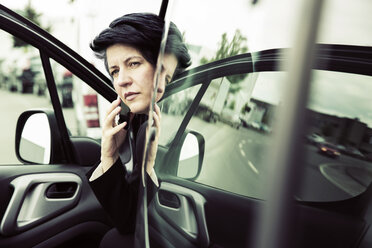 Businesswoman sitting in car, using smart phone - JATF00925