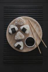 Onigiris, bowl with soy sauce and chopsticks on wooden plate - RTBF00530