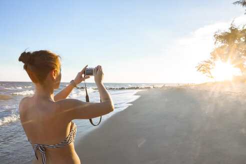 Frau am Strand beim Fotografieren mit ihrer Kamera - MMAF00014