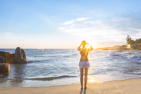 Frau am Strand, die Fotos mit ihrem Smartphone macht - MMAF00016