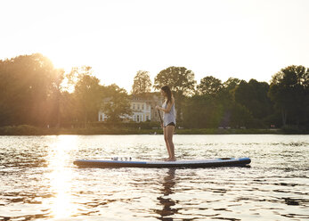 Germany, Hamburg, Young woman on paddleboard enjoying summer - WHF00037