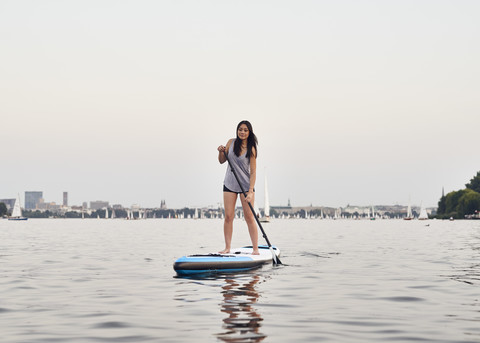 Germany, Hamburg, Young woman on paddleboard enjoying summer stock photo