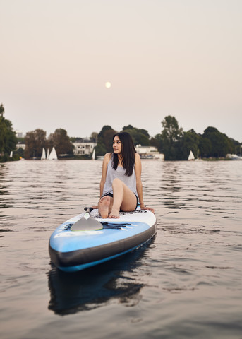 Deutschland, Hamburg, Junge Frau auf Paddelbrett genießt den Sommer, lizenzfreies Stockfoto