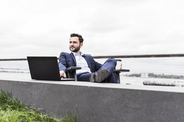 USA, New York, Manager in Manhattan sitting outdoor, using laptop - UUF09201