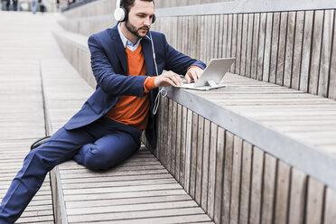 USA, New York City, Businessman sitting on stairs using digital tablet - UUF09227