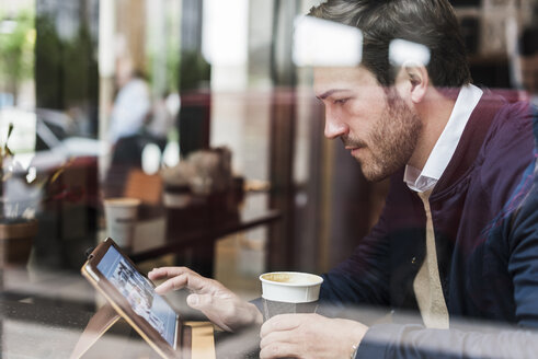 USA, New York City, Geschäftsmann sitzt in einem Café und benutzt ein digitales Tablet - UUF09232