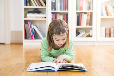 Little girl lying on the floor reading a book - LVF05601