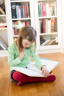 Kleines Mädchen sitzt auf dem Boden und liest ein Buch - LVF05602