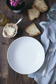 Leerer Teller, Parmesan, Weißbrotscheiben, Tuch und Gabel auf dunklem Holz - DAIF00006