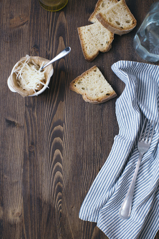 Parmesan, slices of white bread, cloth and fork on dark wood stock photo