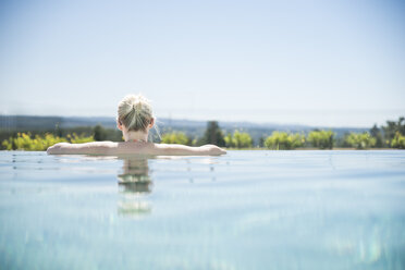 Frau steht im Infinity-Pool und schaut in die Ferne - CHPF00328