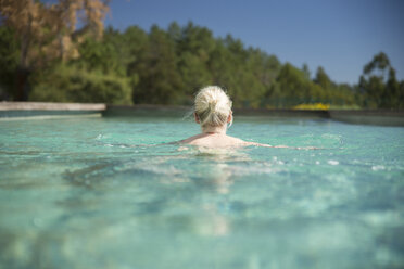 Frau schwimmt im Pool, Rückansicht - CHPF00329