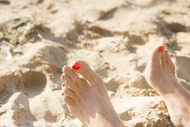 Feet with red nail varnish in sand - CHPF00336
