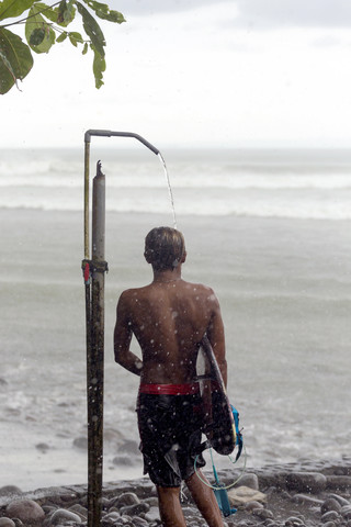 Indonesien, Bali, Surfer beim Duschen im Regen, lizenzfreies Stockfoto