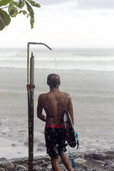 Indonesia, Bali, surfer taking a shower in rain - KNTF00583