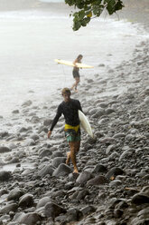 Indonesien, Bali, zwei Surfer tragen Surfbretter im Regen - KNTF00584