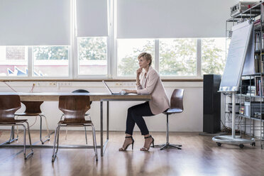 Businesswoman using laptop in modern conference room - RIBF00587