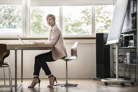 Businesswoman using laptop in modern conference room stock photo