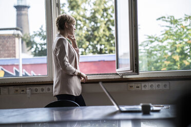 Geschäftsfrau, die im Büro mit einem Handy telefoniert - RIBF00593