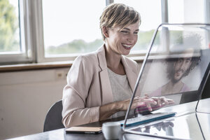 Businesswoman using futuristic modern computer in office - RIBF00604