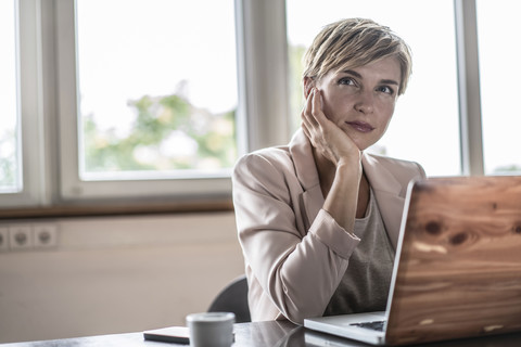 Geschäftsfrau mit Laptop im Konferenzraum denkt nach, lizenzfreies Stockfoto