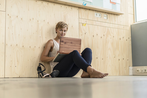 Geschäftsfrau mit Laptop auf dem Boden, lizenzfreies Stockfoto