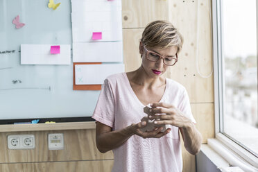 Frau arbeitet an Holzbausteinen in einem modernen Büro - RIBF00653