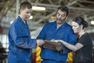 Mechanics working at fire brigade workshop reading check list - ZEF11696