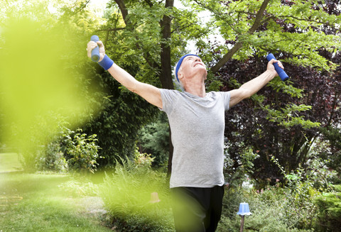 Senior man doing fitness training with dumbells in garden stock photo