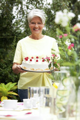 Ältere Frau serviert Sahnetorte im Garten - MFRF00761
